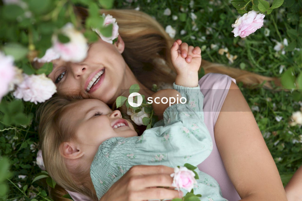 Woman in pink tank top hugging daughter in green dress