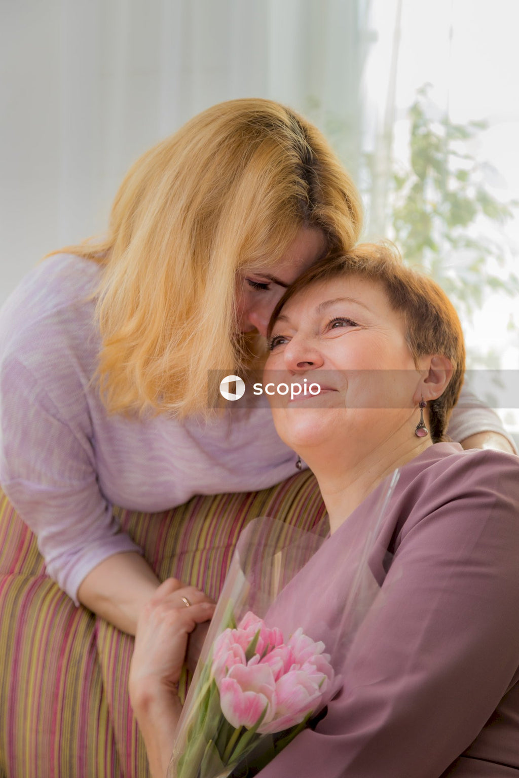 Woman in purple long sleeve shirt hugging woman in pink long sleeve shirt