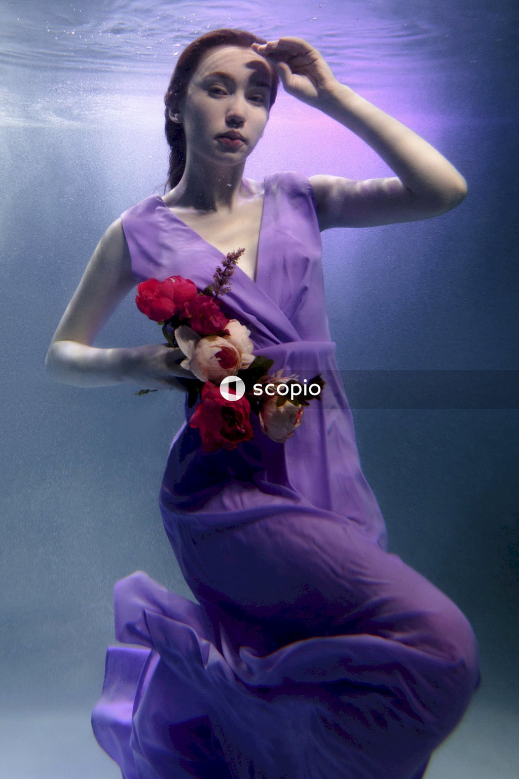 A woman in a purple dress holding bouquet of red roses
