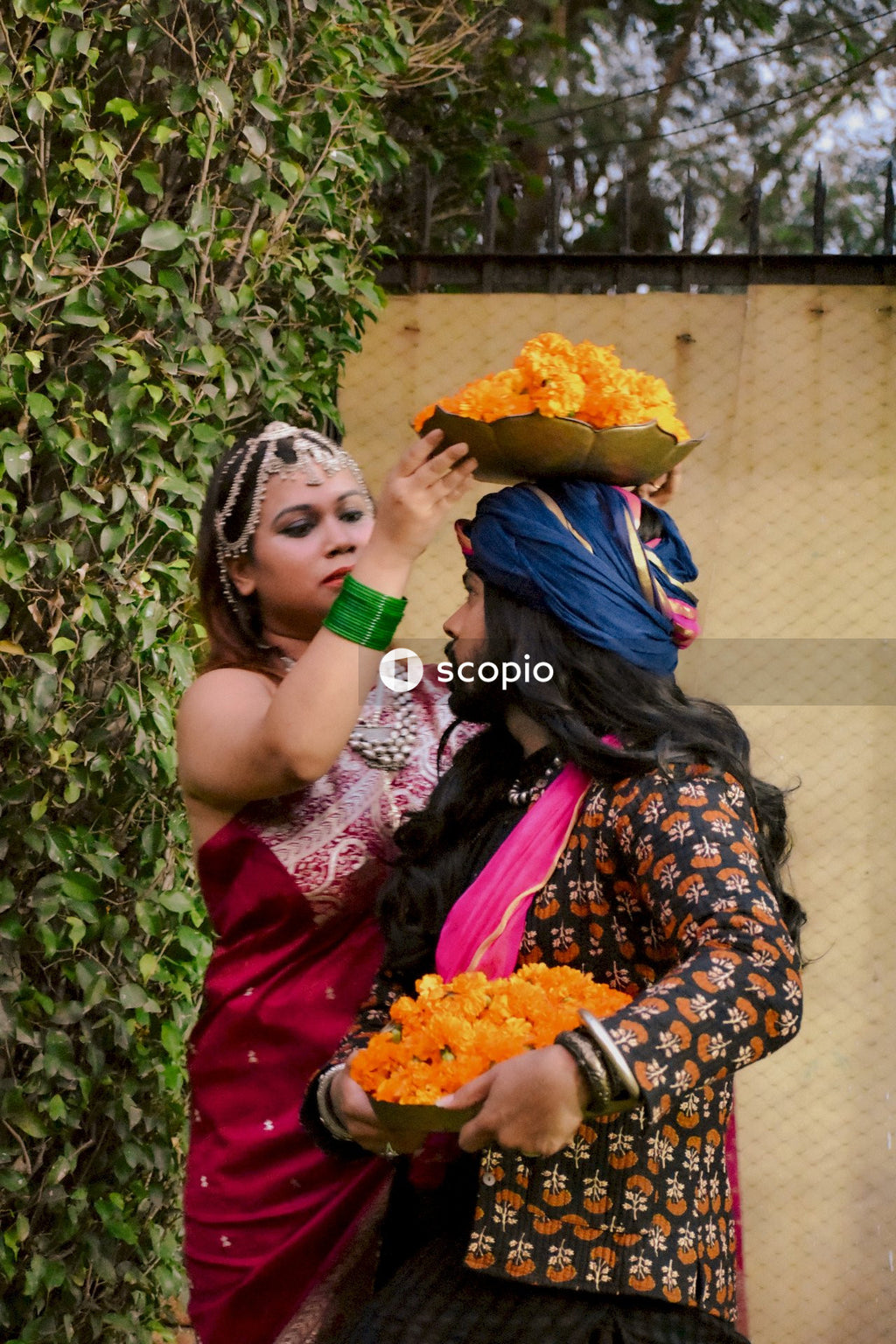 Indian couple holding baskets of marigold flowers standing outdoor