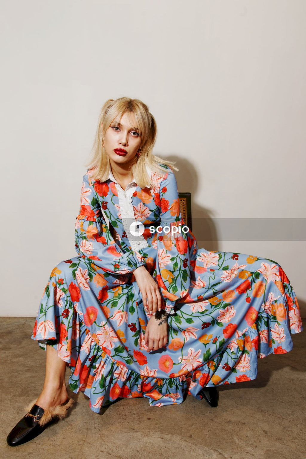 Woman in red and white floral dress sitting on brown wooden chair