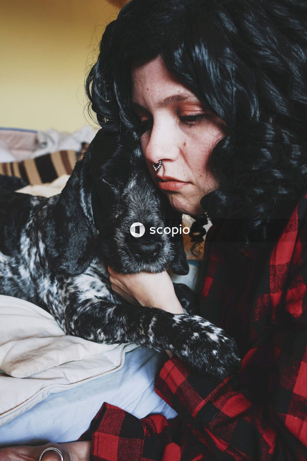 Woman in red shirt hugging black and white short coated dog