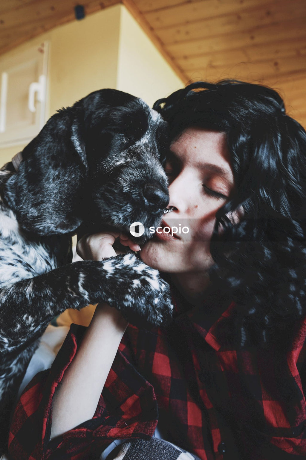 Woman in red shirt hugging black and white short coated dog