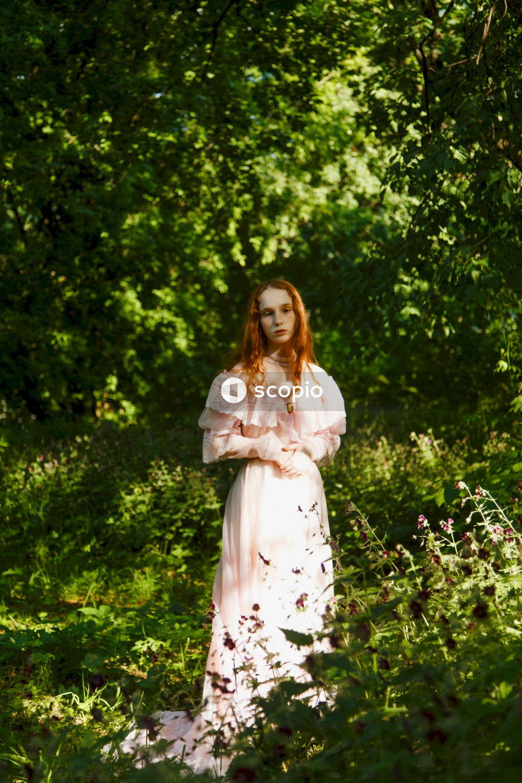 Woman in white and black floral dress standing on green grass field