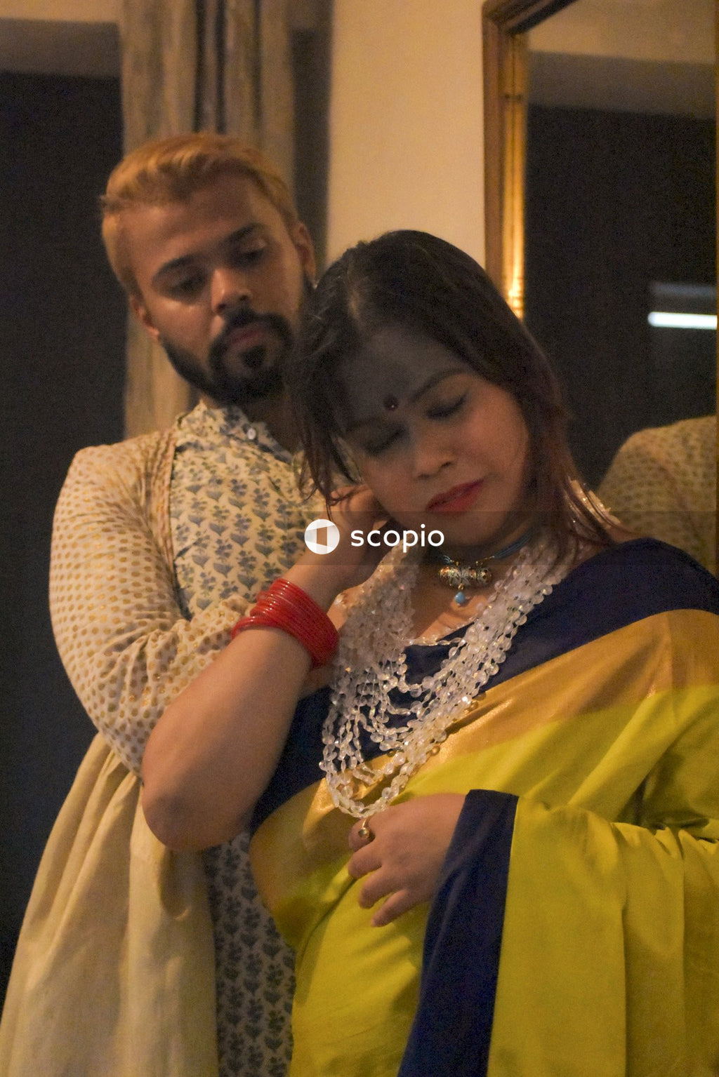 Woman in sari standing in front of man indoor