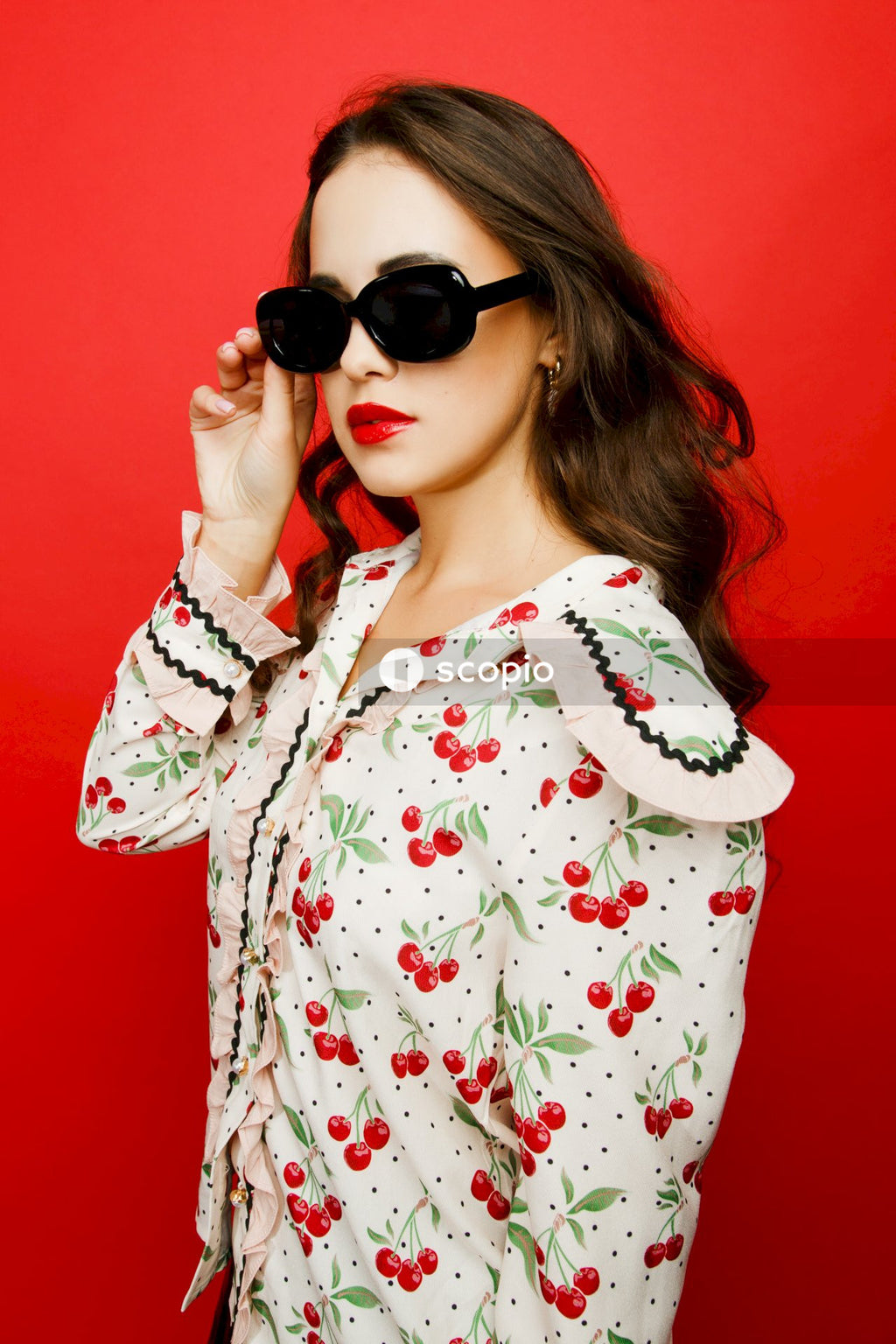 Woman in white and red floral button up long sleeve shirt wearing black sunglasses