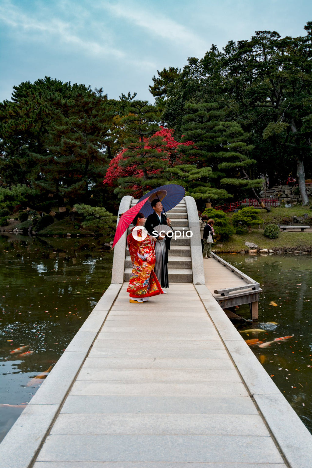 Japanese couple in their traditional outfit standing on concrete pathway in a garden