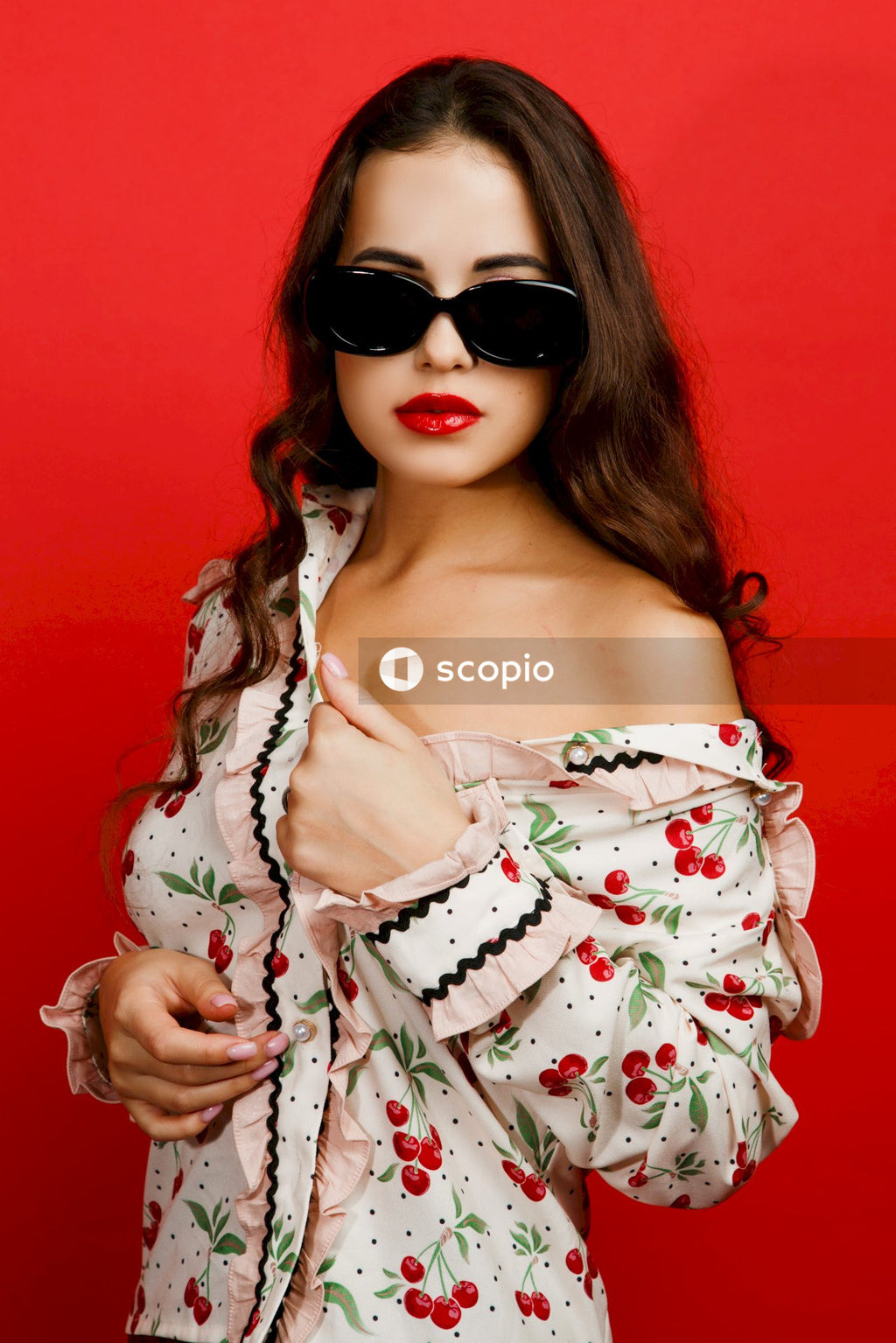 Woman in white and red floral dress wearing black sunglasses