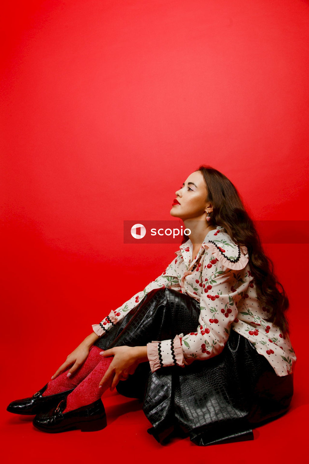 Woman in white and red floral long sleeve shirt sitting on red chair