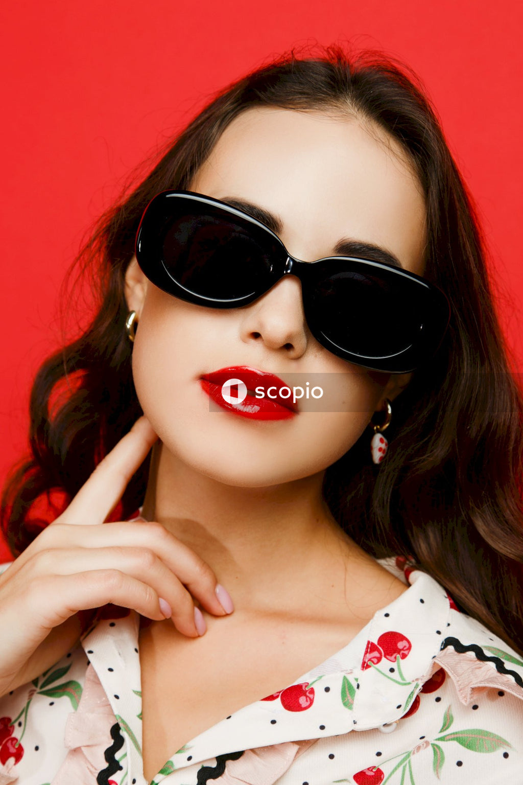 Woman in white and red polka dot shirt wearing black sunglasses