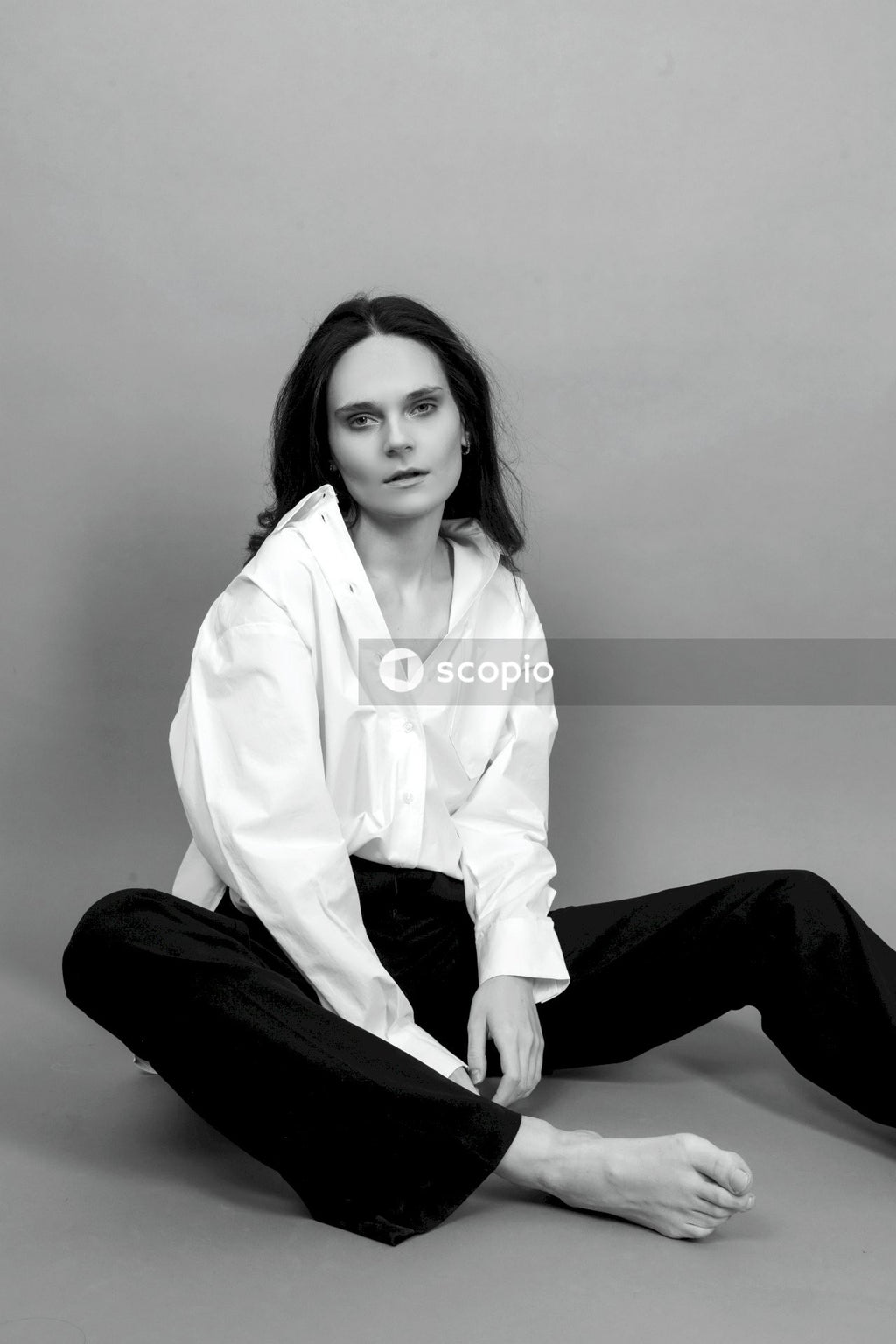 Woman in white button up long sleeve shirt and black pants sitting on floor