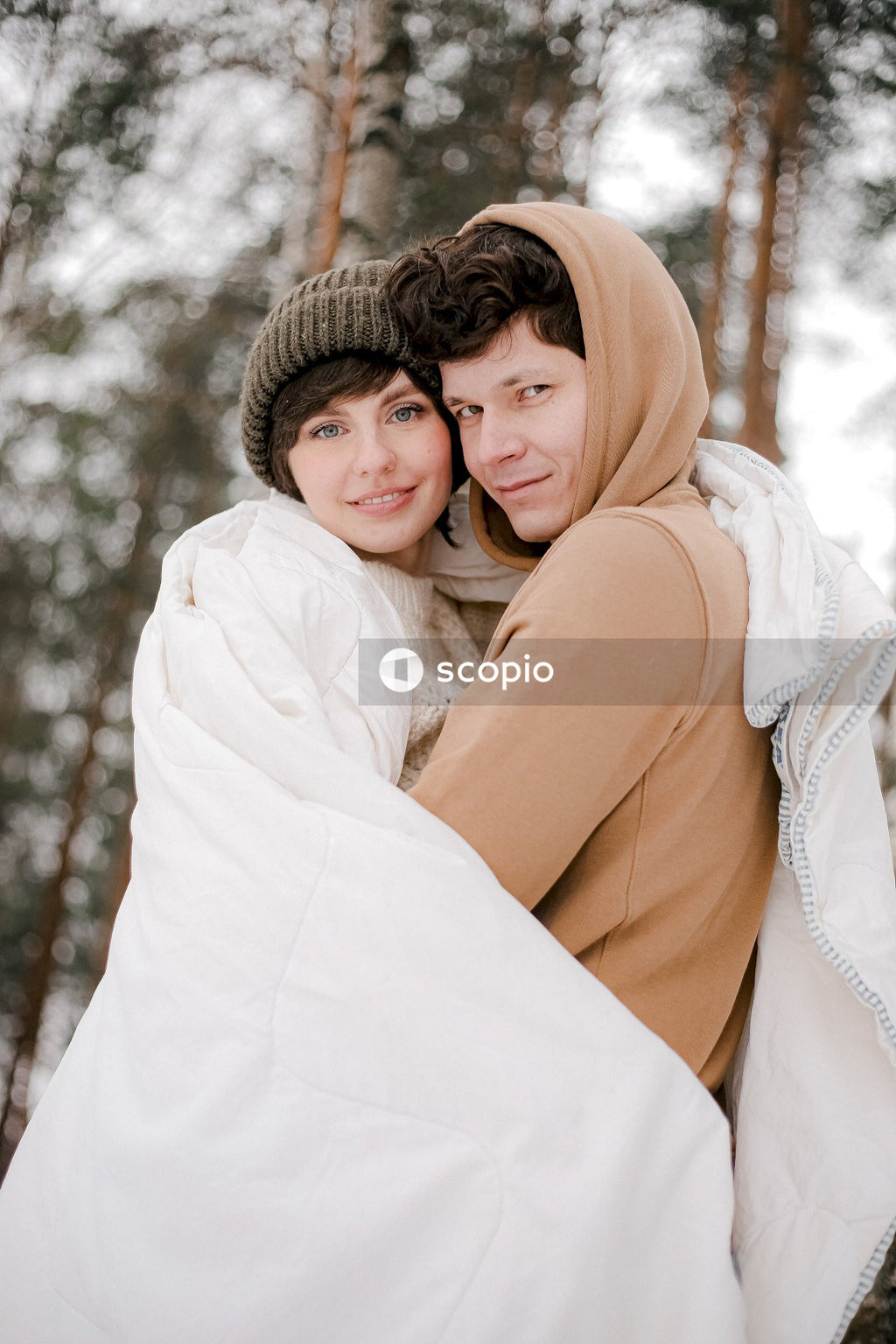 Young couple hugging each other in snow covered woods