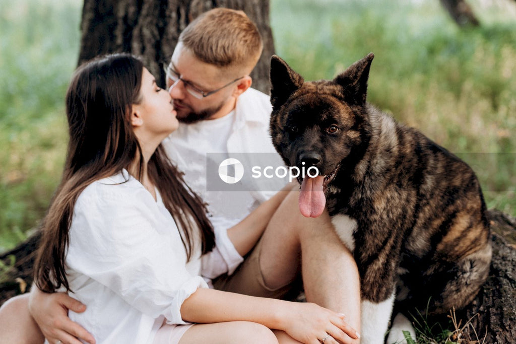 Woman in white dress hugging brown and black short coated dog