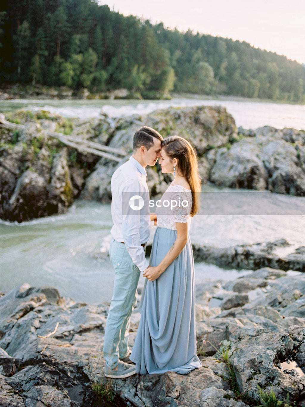 Woman in white dress hugging woman in white dress on rocky shore