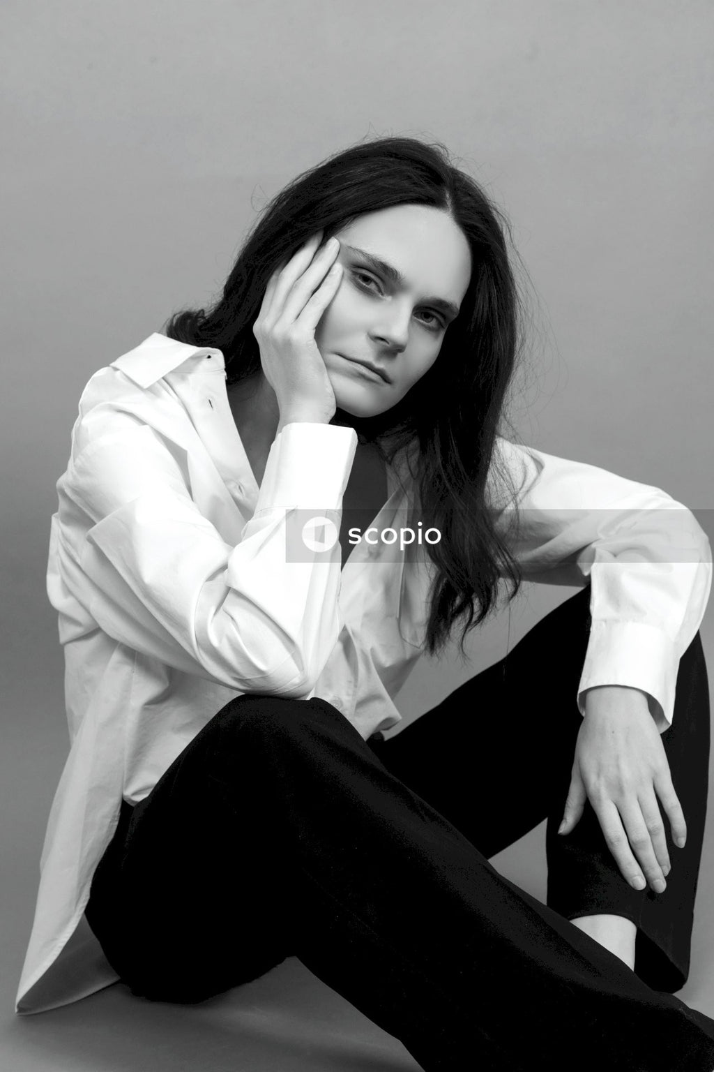 Woman in white dress shirt and black pants sitting on floor