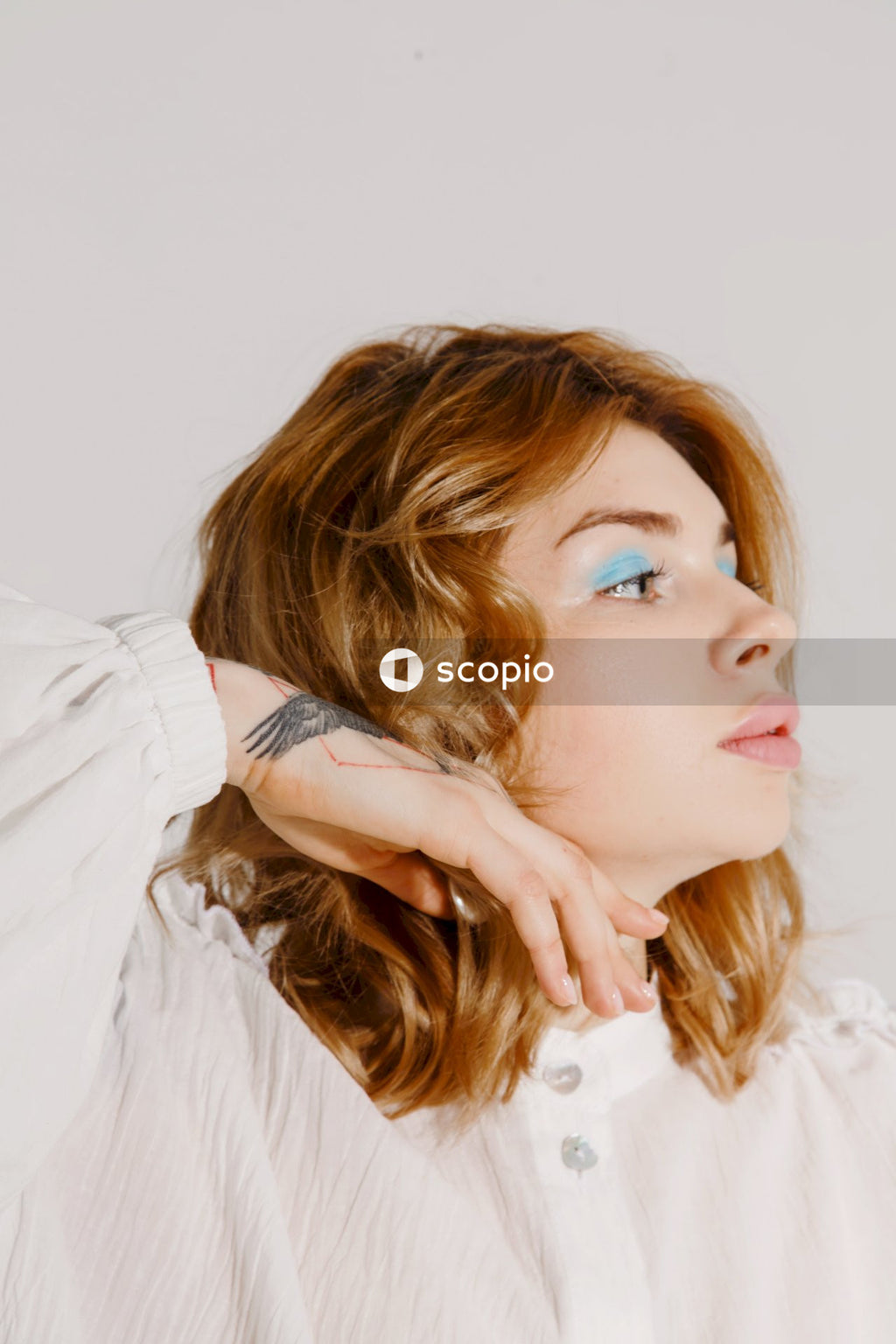 Woman in white dress shirt covering her face with her hair