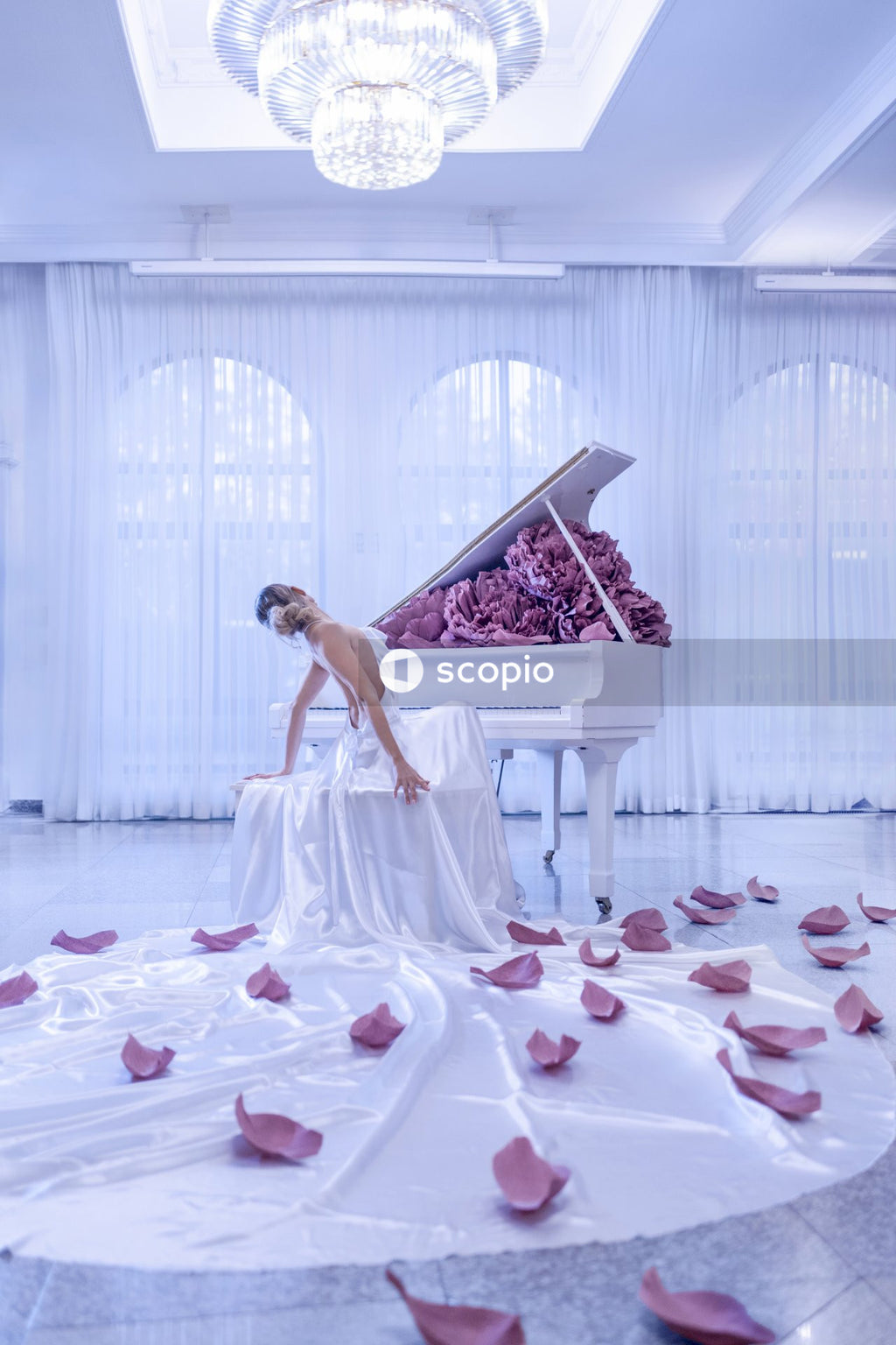 Woman in white dress sitting on white piano