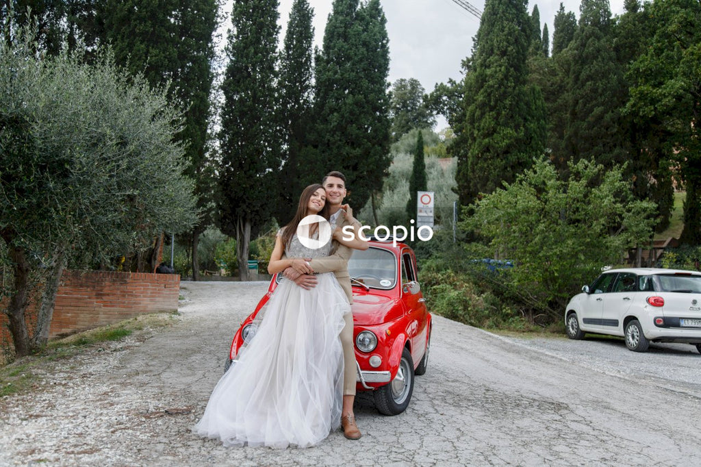 Young married couple doing a photoshoot near small red car