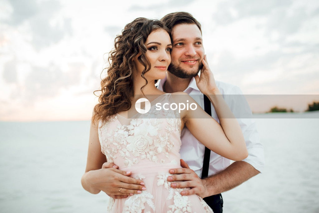 Woman in white floral dress hugging man in black suit