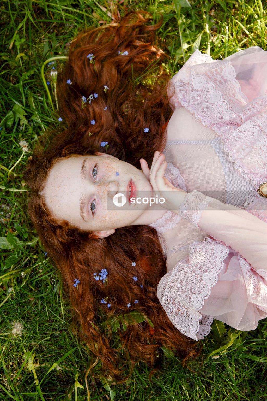 Woman in white floral lace dress lying on green grass