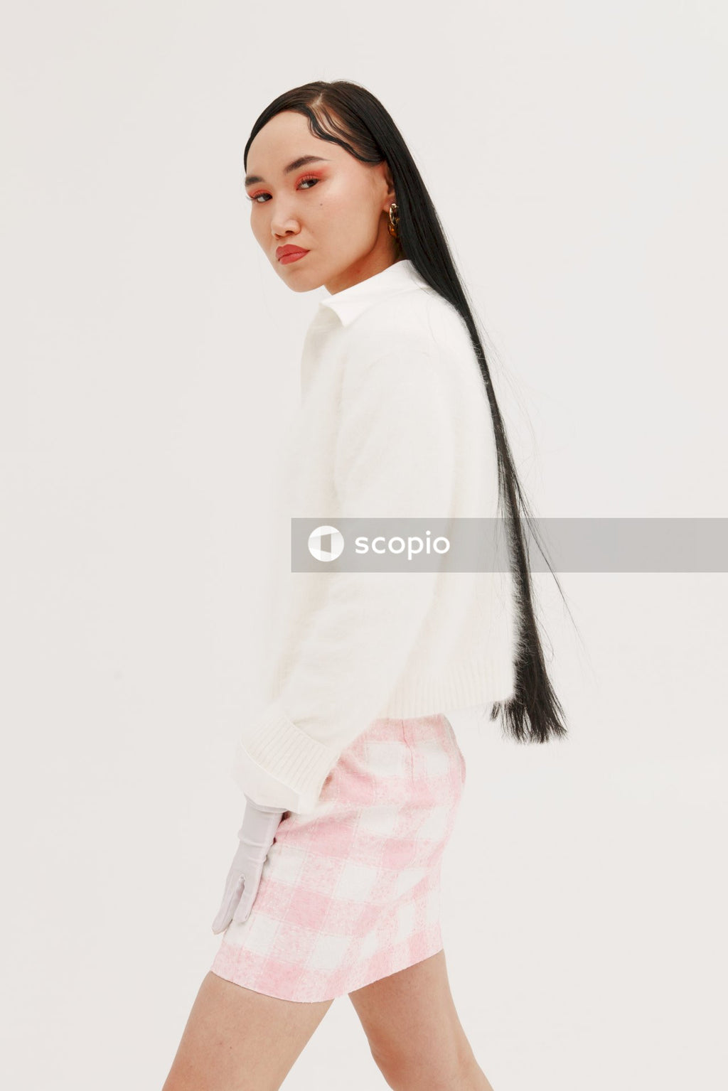 Woman in white long sleeve shirt and pink and white plaid skirt