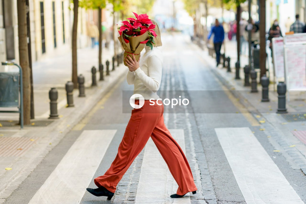 Woman in white long sleeve shirt and red pants with green yellow and red floral head