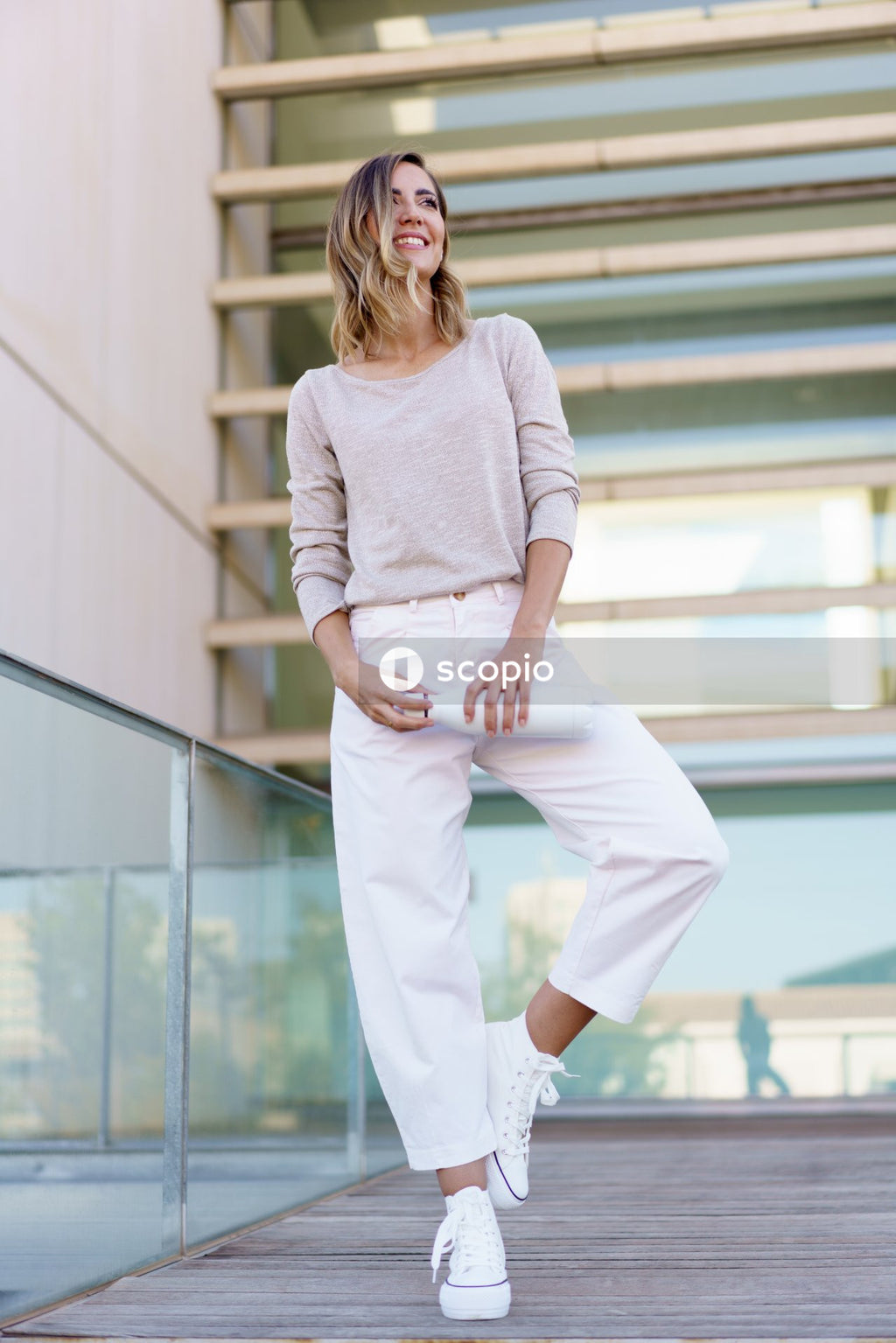 Woman in white long sleeve shirt and white pants standing on white concrete staircase