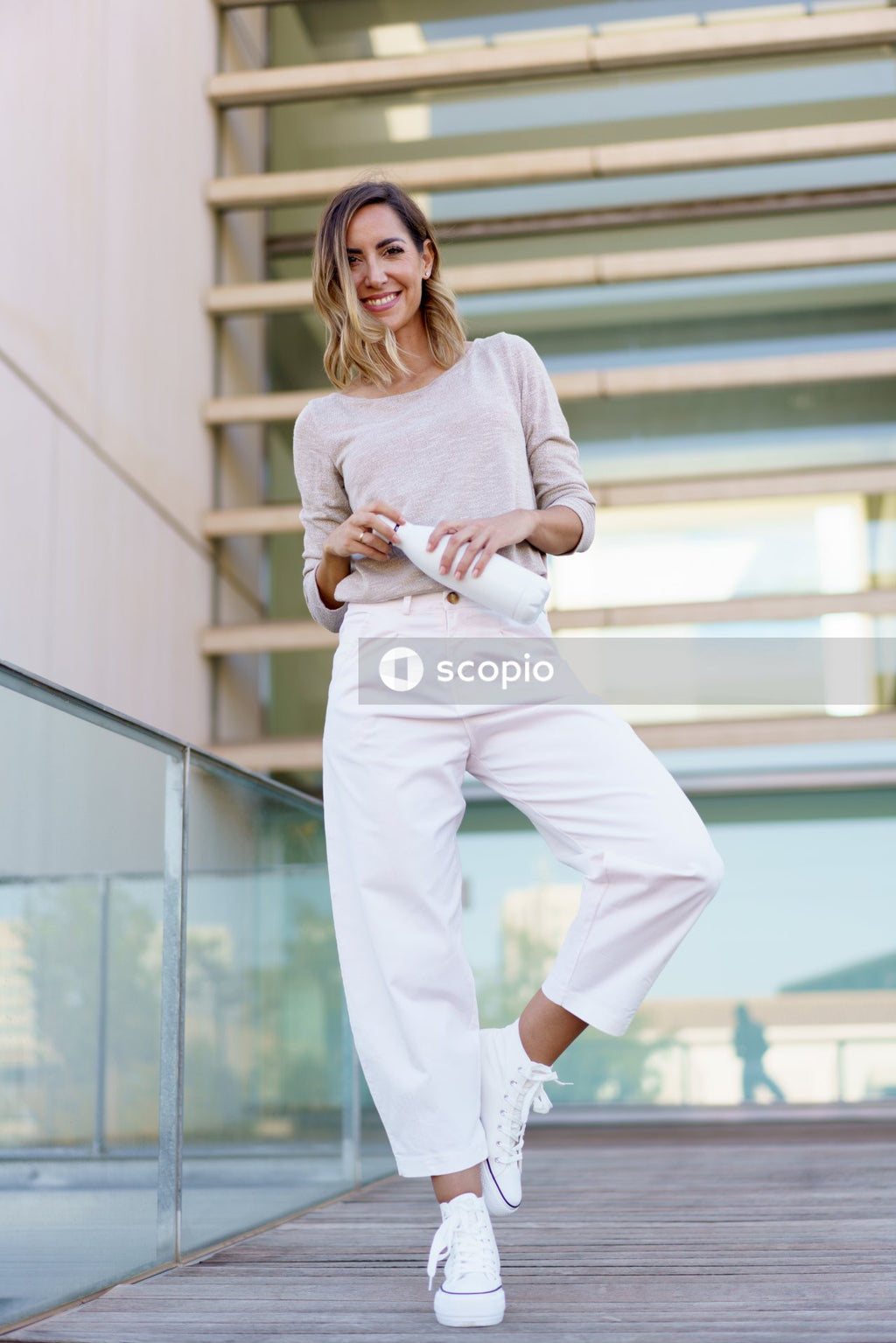 Woman in white long sleeve shirt and white pants standing on white staircase