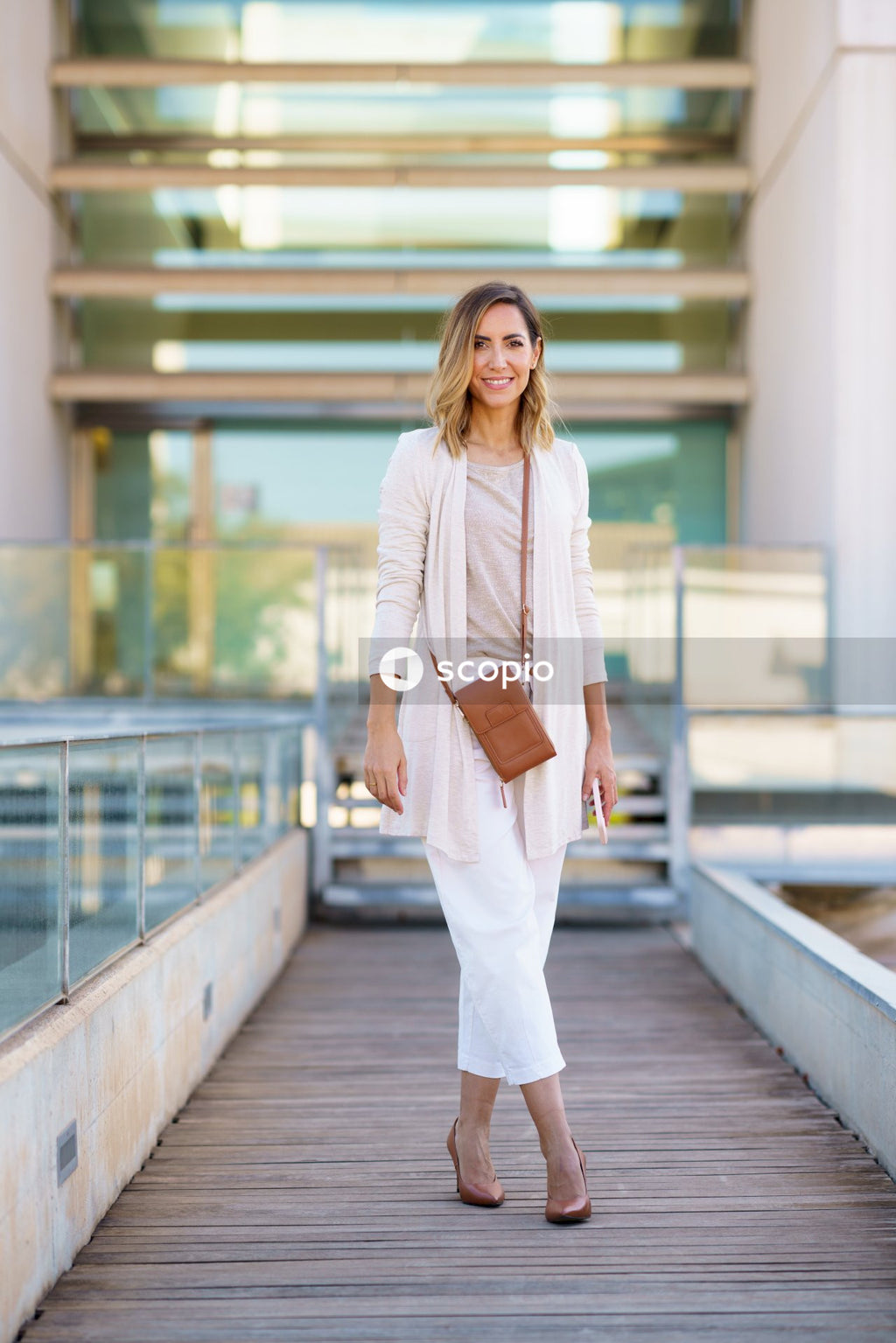 Woman in white long sleeve shirt and white skirt standing on brown wooden bridge