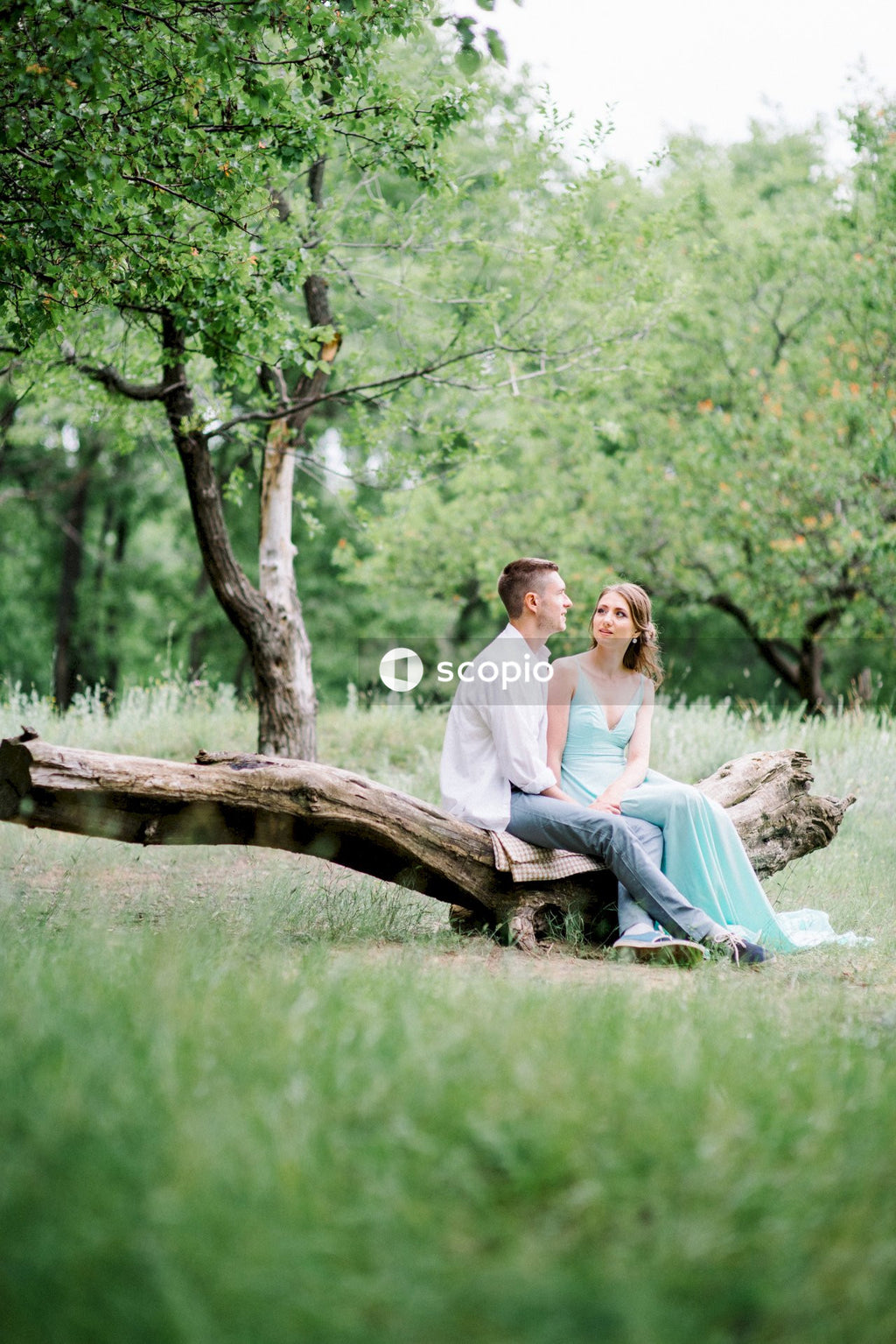 Woman in white long sleeve shirt sitting on brown wooden log