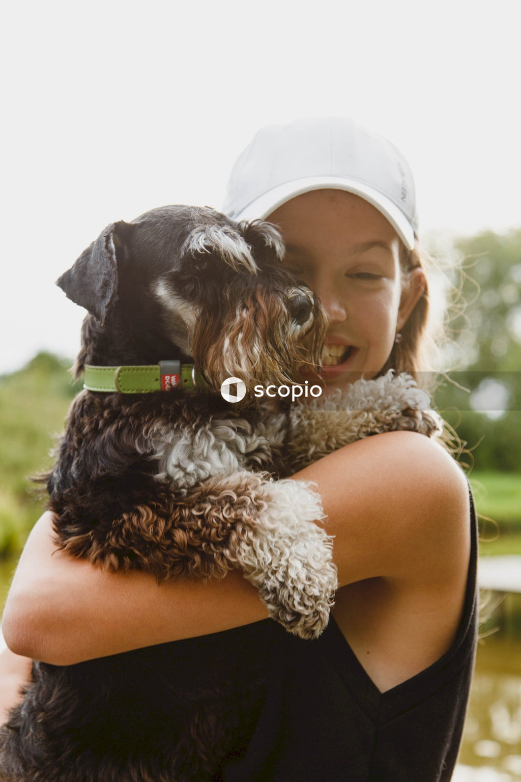 Woman in white shirt hugging black and white long coated small dog