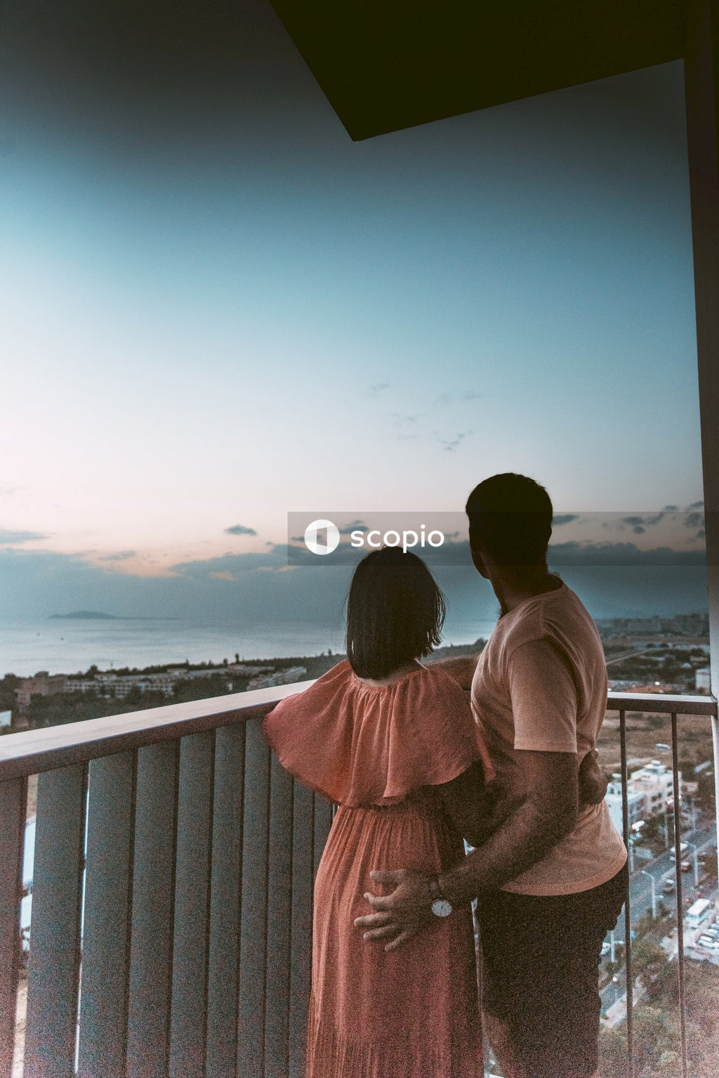 Man and woman hugging and standing on balcony looking away