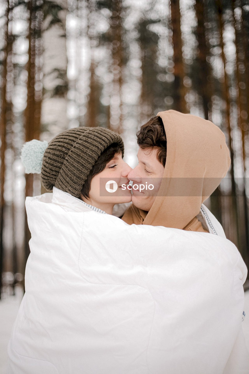 Young couple kissing each other in snow covered woods