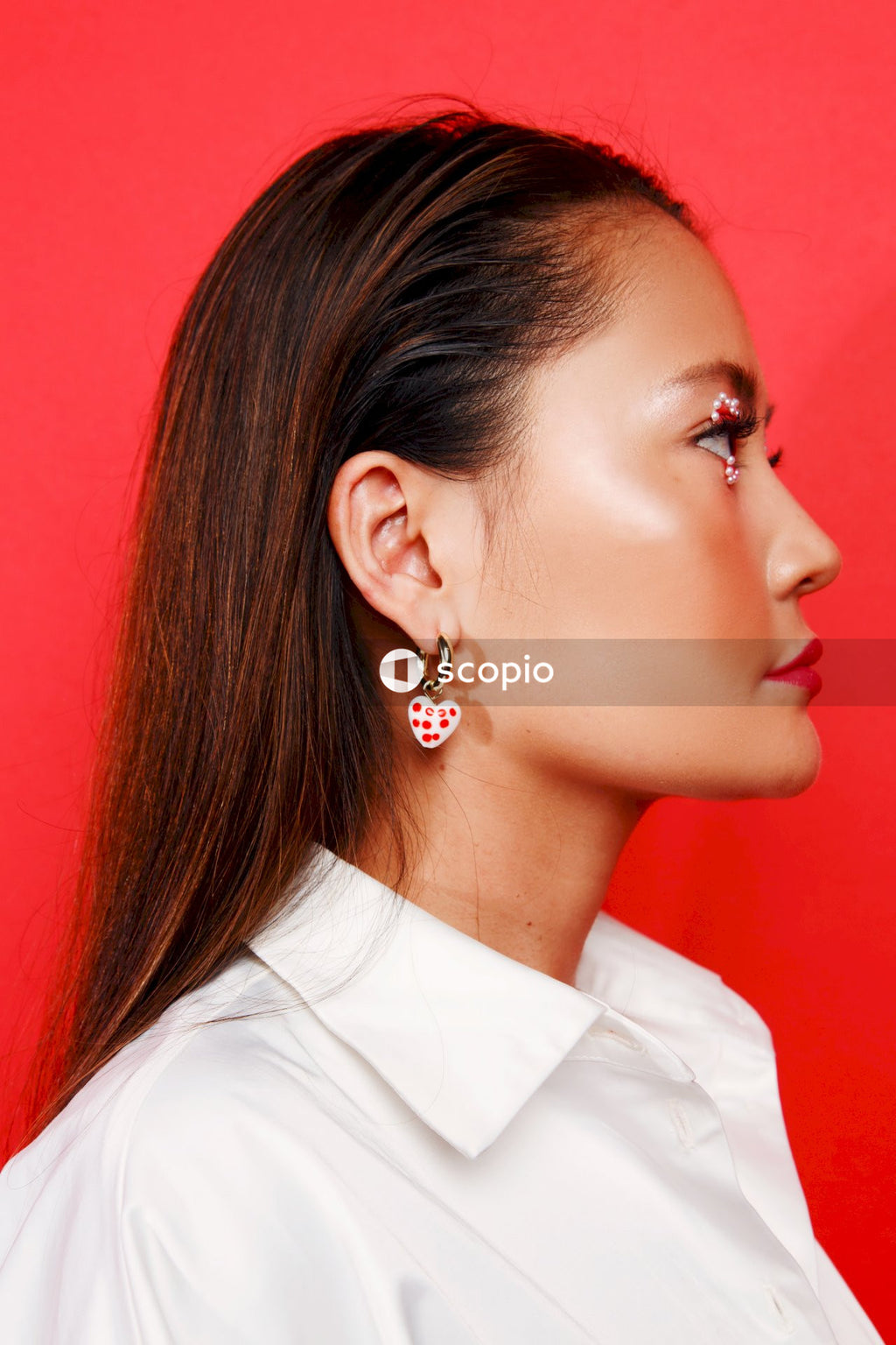 Woman in white shirt wearing silver and diamond stud earring