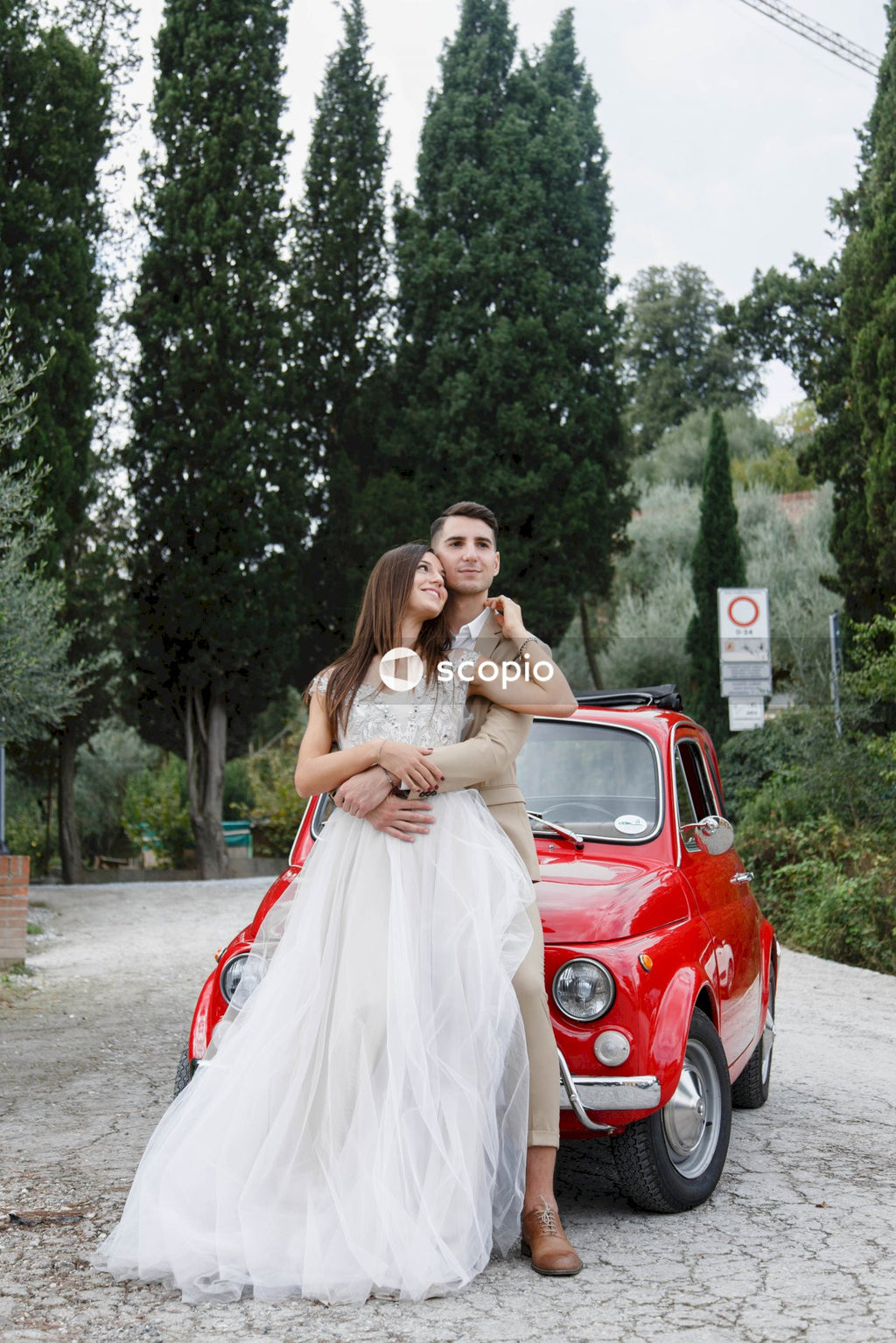 Young married couple doing a photoshoot near small red car