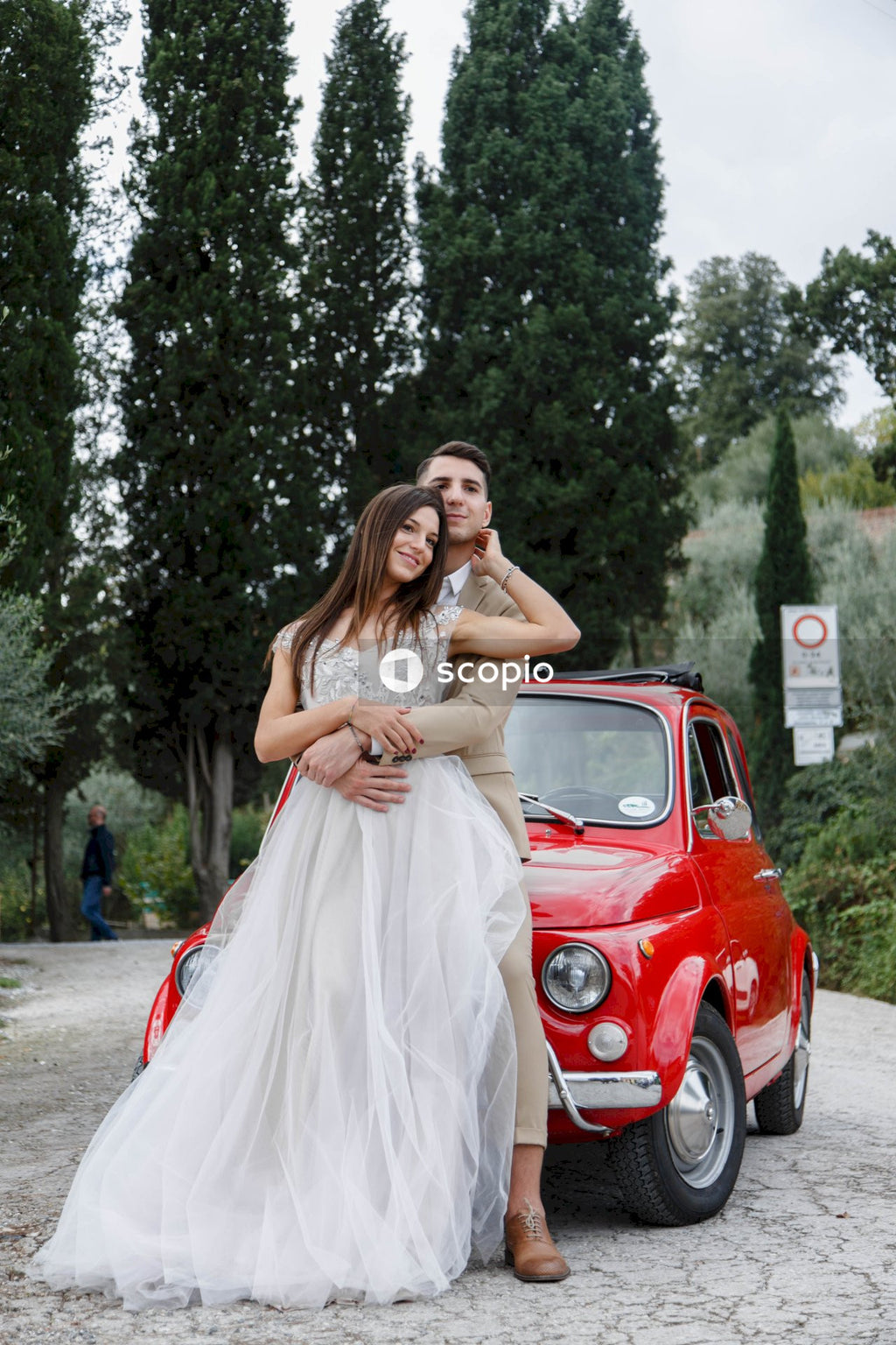 Young married couple doing a photoshoot near small red car