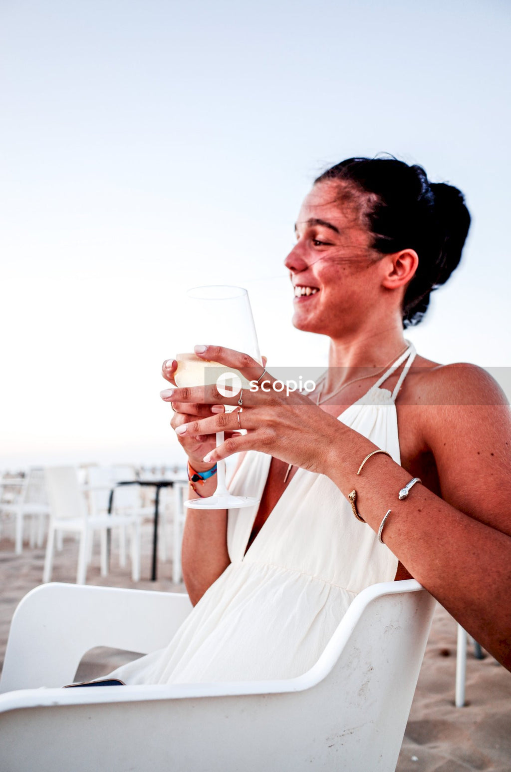 Woman in white spaghetti strap dress holding clear drinking glass