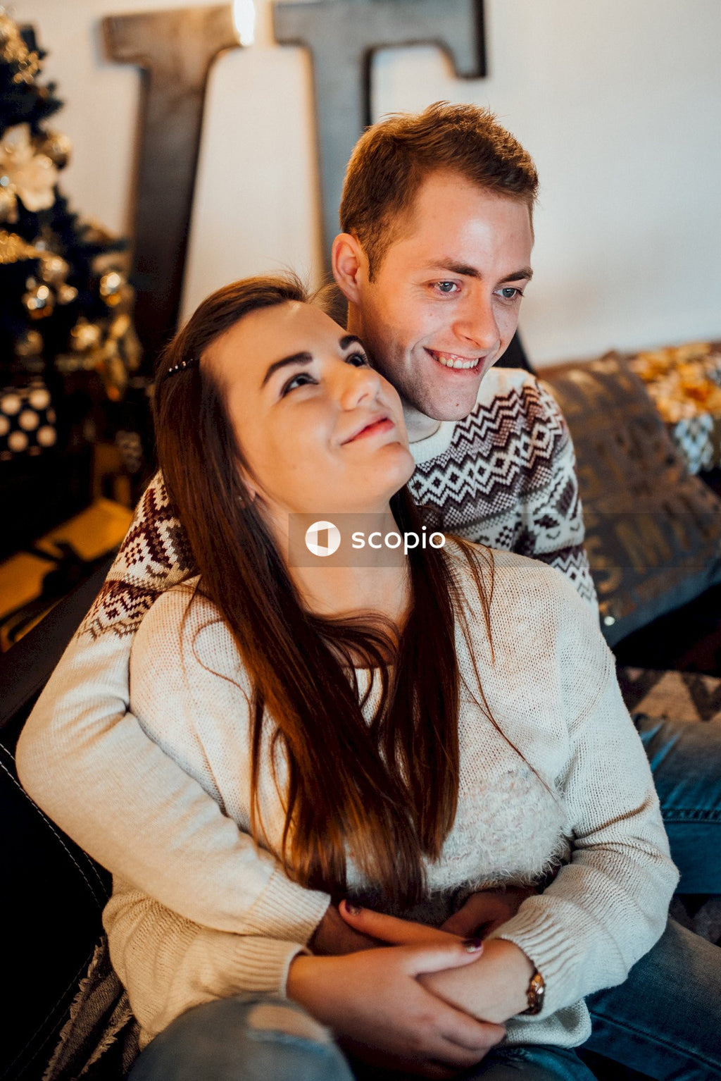 Woman in white sweater hugging man in gray sweater