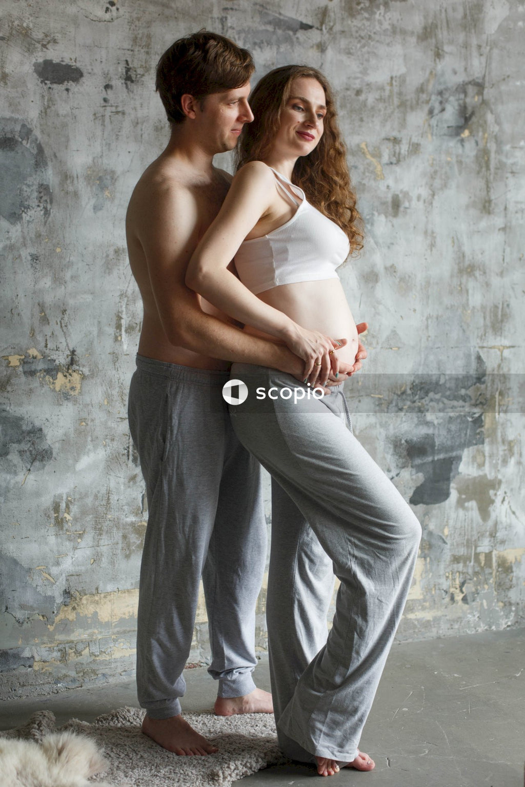 Couple stand next to a gray concrete wall