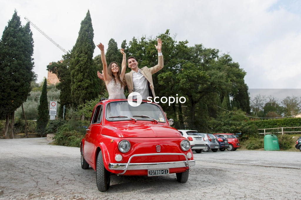 Young married couple doing a photoshoot near small red car