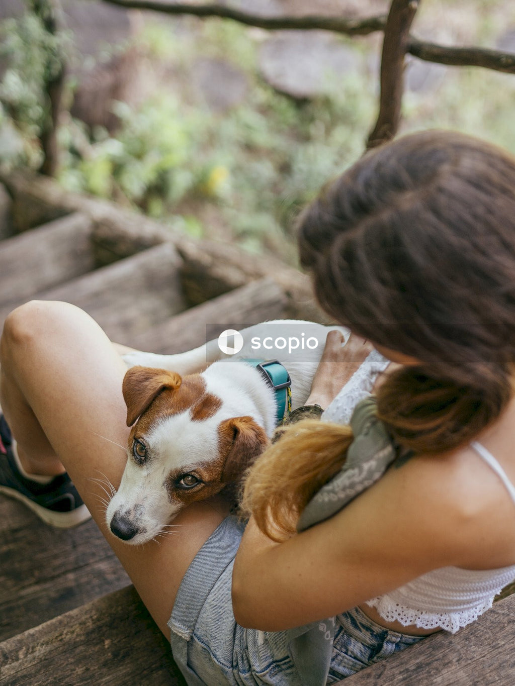 Woman in white tank top hugging white and brown short coat small dog