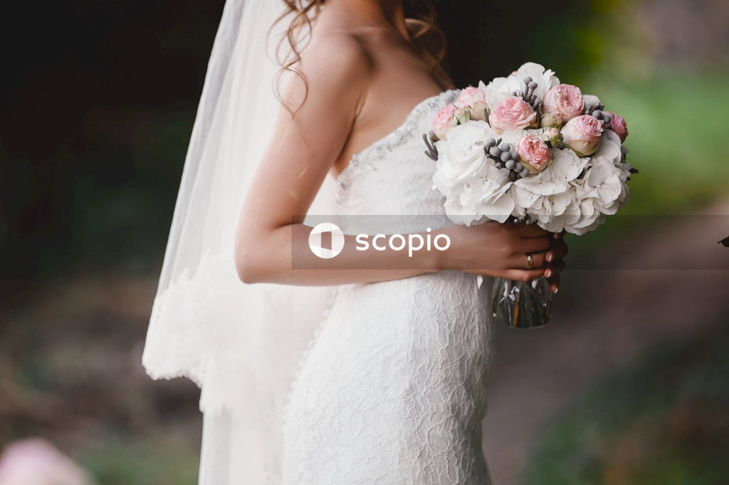 Woman in white wedding dress holding bouquet of white flowers