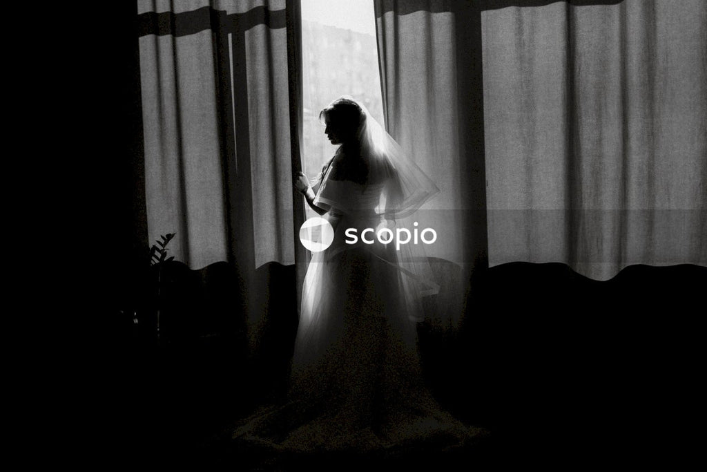 Woman in white wedding dress standing near window