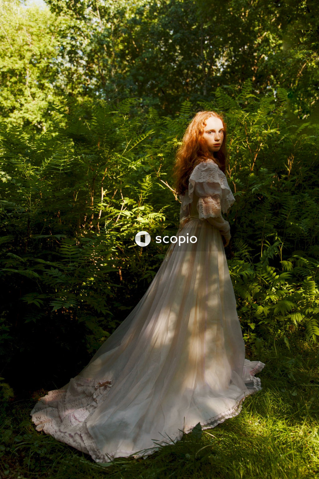 Woman in white wedding dress standing on green grass field