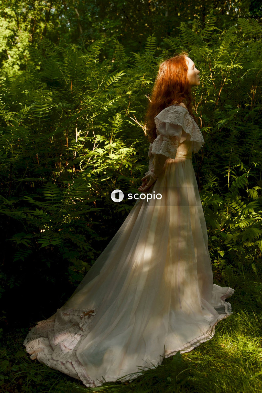 Woman in white wedding dress standing on green grass field