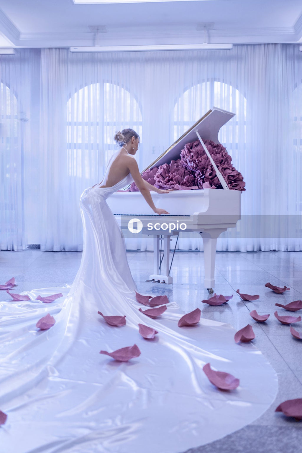 Woman in white wedding dress standing on white grand piano