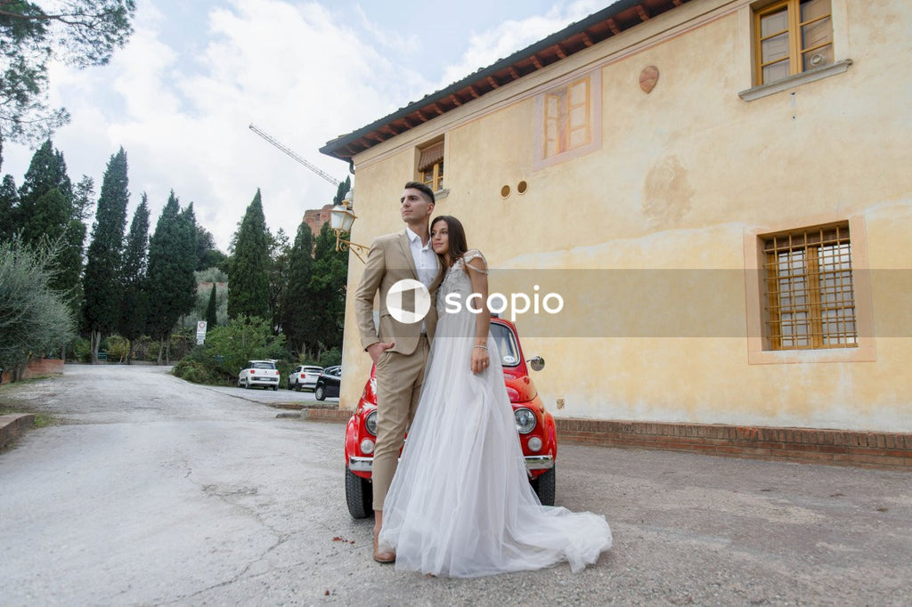 Young married couple doing a photoshoot near small red car