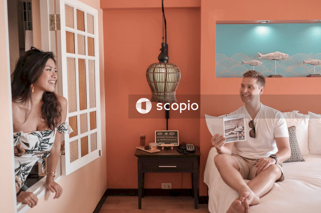 Woman in window near man sitting on bed holding brochure