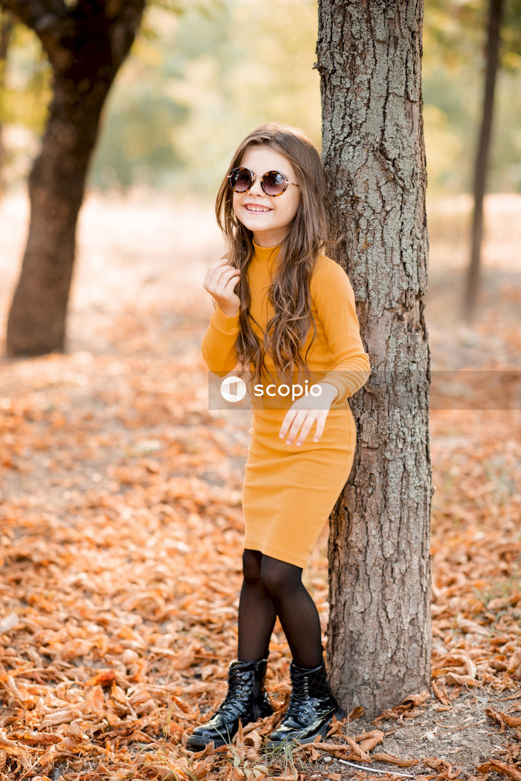 Woman in yellow dress standing beside tree
