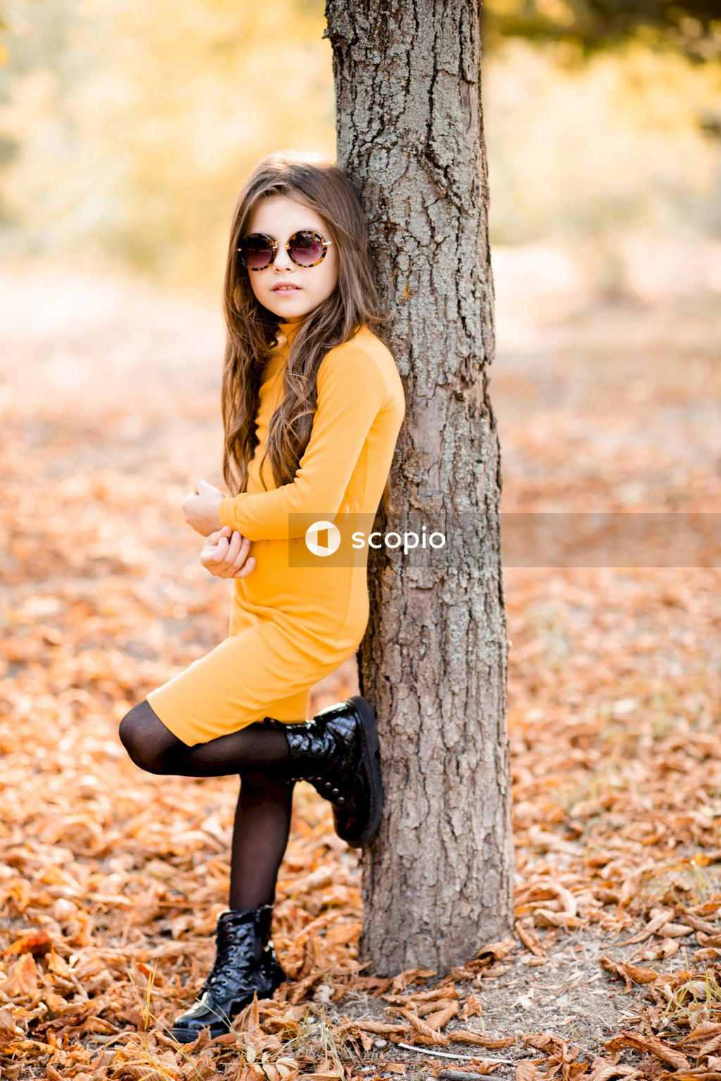 Woman in yellow long sleeve shirt and black pants sitting on tree trunk
